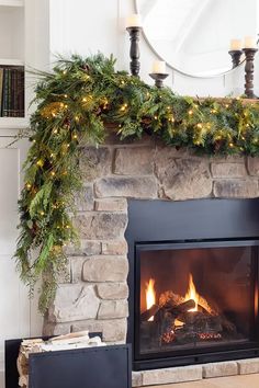 a fireplace decorated with greenery and lit candles