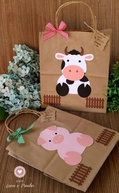 two brown paper bags with pink and black cows on them, one has a bow