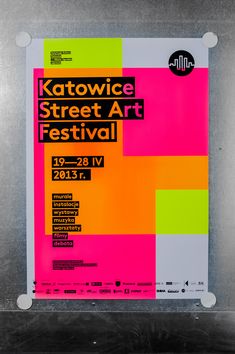 the poster for the festival is displayed in front of a metal frame with colorful squares on it