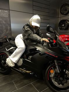 a man sitting on top of a motorcycle in a showroom with other motorcycles behind him