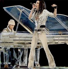 a woman standing next to a piano on top of a stage