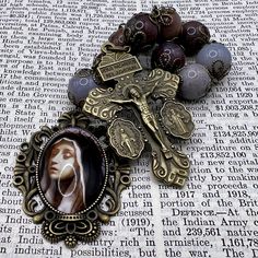 This single-decade rosary, handmade in Scotland, is a striking piece that combines deep spiritual symbolism with an elegant design. The beads are made from large 12mm dusk purple agate, giving the rosary a rich, mysterious appearance. The metalwork, crafted from antiqued brass, enhances the vintage Victorian Gothic feel, making it a unique and captivating devotional item. The rosary features a detailed Pardon Crucifix, which includes inscriptions of powerful prayers. The Pardon Crucifix is deepl Spiritual Rosary With Natural Stones As Gift, Spiritual Beaded Rosary For Jewelry Making, Bohemian Rosary With Natural Stones For Gifts, Spiritual Round Beads Rosary For Jewelry Making, Spiritual Rosary Bracelet With Round Beads For Jewelry Making, Spiritual Agate Beads For Jewelry Making, Spiritual Beaded Rosary Bracelet With Crucifix, Bohemian Cross Rosary Bracelet Gift, Handmade Crucifix Rosary For Meditation