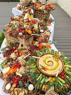 an assortment of food is laid out on a long table with white clothed cloths