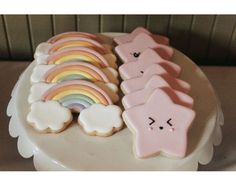 there are many decorated cookies on the cake plate with rainbows and clouds in them