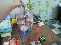 a person is holding an electronic device in front of a glass bottle with lights inside