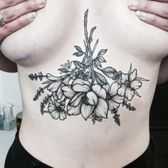 a woman's stomach with flowers and leaves tattooed on the side by an artist