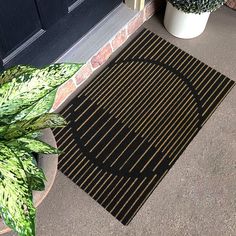 a black door mat sitting next to a potted plant