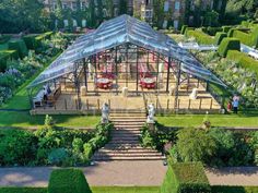 an aerial view of a glass house in the middle of a lush green garden with stairs leading up to it