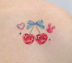 the back of a woman's shoulder with tattoos on it and two cherries