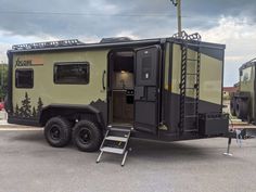 an rv parked in a parking lot with the door open and ladder up to it