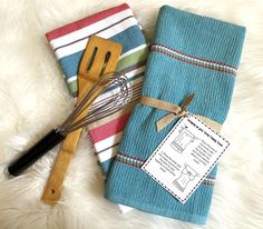 two kitchen towels with wooden utensils next to each other