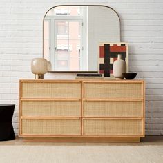 a white brick wall with a large mirror on top of it next to a dresser