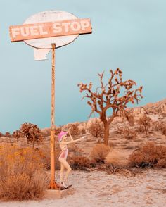 a woman standing next to a sign in the desert