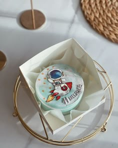 a space themed cookie in a box on top of a table with other items around it