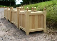 four wooden planters lined up on the side of a road in front of some grass