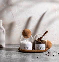 salt and pepper in glass jars with wooden spoon