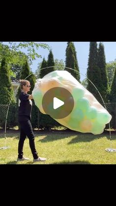 a person holding a large kite in the air on top of a grass covered field