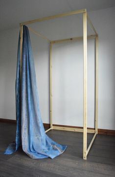 an empty room with a blue sheet on the floor and a wooden frame in the middle