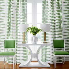 two chairs and a table in front of a window with green drapes on it