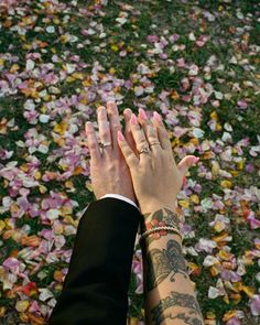 two people with their hands together in front of some pink and yellow flowers on the ground