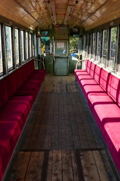 the inside of a bus with red seats and wood flooring on both sides is empty