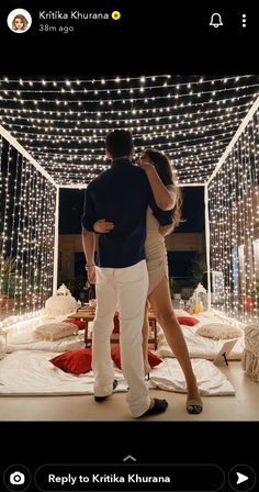 a man and woman standing in front of a string of lights