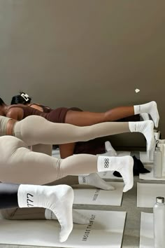 two women in white tights and leggings are doing exercises on the floor