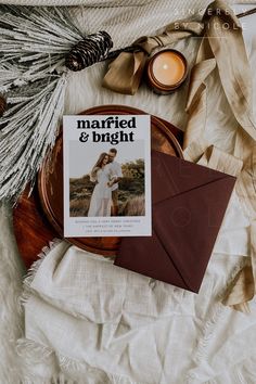 a magazine sitting on top of a bed next to a candle and some dried flowers