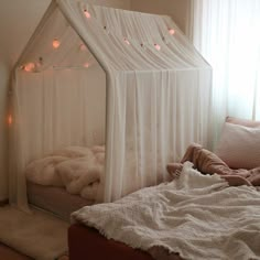 a bed with a white canopy over it and lights on the wall behind it in a bedroom