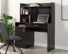 a computer desk with a laptop on it in front of a bookcase and chair