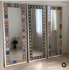 three mirrors sitting on top of a wooden floor next to a vase filled with flowers