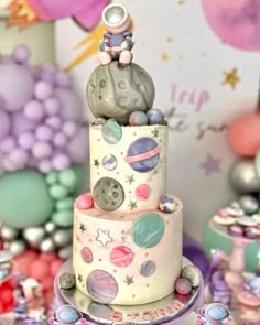 there is a cake that has planets on it and an astronaut sitting on the top