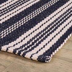 a blue and white striped rug on the floor with wood flooring in the background