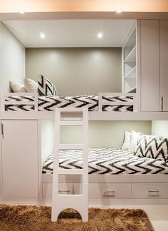 a bunk bed in a room with white cabinets and black and white patterned bedspread