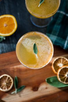 two glasses filled with orange juice on top of a wooden cutting board