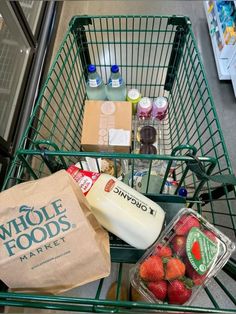 a shopping cart filled with groceries and drinks next to a bag of milk, juice, and strawberries