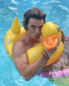 a man holding an inflatable rubber duck floating on top of a swimming pool