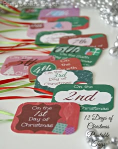 christmas gift tags are lined up on a table with silver balls and streamers in the background