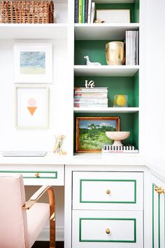 a pink chair sitting in front of a white desk with green and gold trim on it