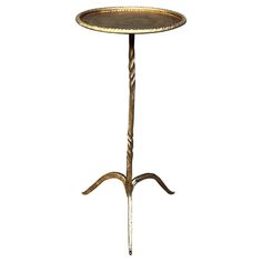 a small table with a metal base and gold leaf decoration on the top, against a white background