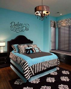 a bedroom decorated in blue and black with zebra print on the bedding, chandelier