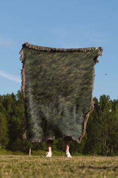 a person standing under a large blanket in the grass