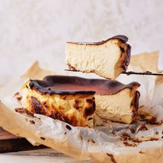 two pieces of cheesecake being lifted with a toothpick from a wooden tray