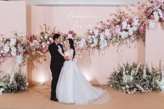 a bride and groom are standing in front of a floral arch at their wedding reception