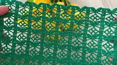 a green crochet doily with yellow tulips in the background