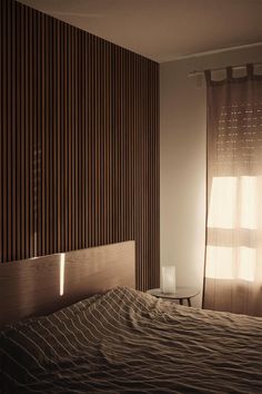 an empty bed in front of a wooden wall