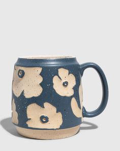 a blue and white coffee mug with flowers on the outside, sitting in front of a gray background