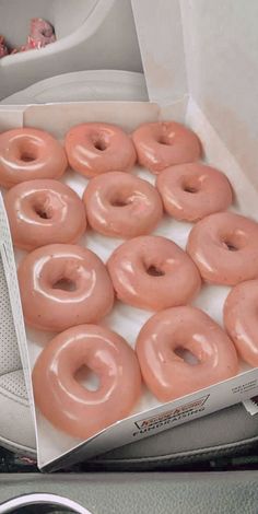 a box filled with pink frosted donuts sitting on top of a car dashboard