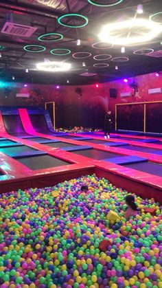 an indoor trampoline with lots of balls all over the floor and lights on