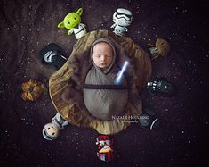 a baby in a star wars costume surrounded by toys and stuffed animals on a black background